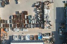Foto: Luftaufnahme eines Schrottplatzes mit zahlreichen Containern, gefüllt mit Metall- und Aluminiumschrott. Stapel und Haufen von recycelbarem Material.