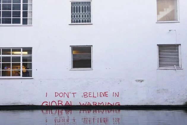 Napis na podtopionym budynku "I don't believe in global warming"