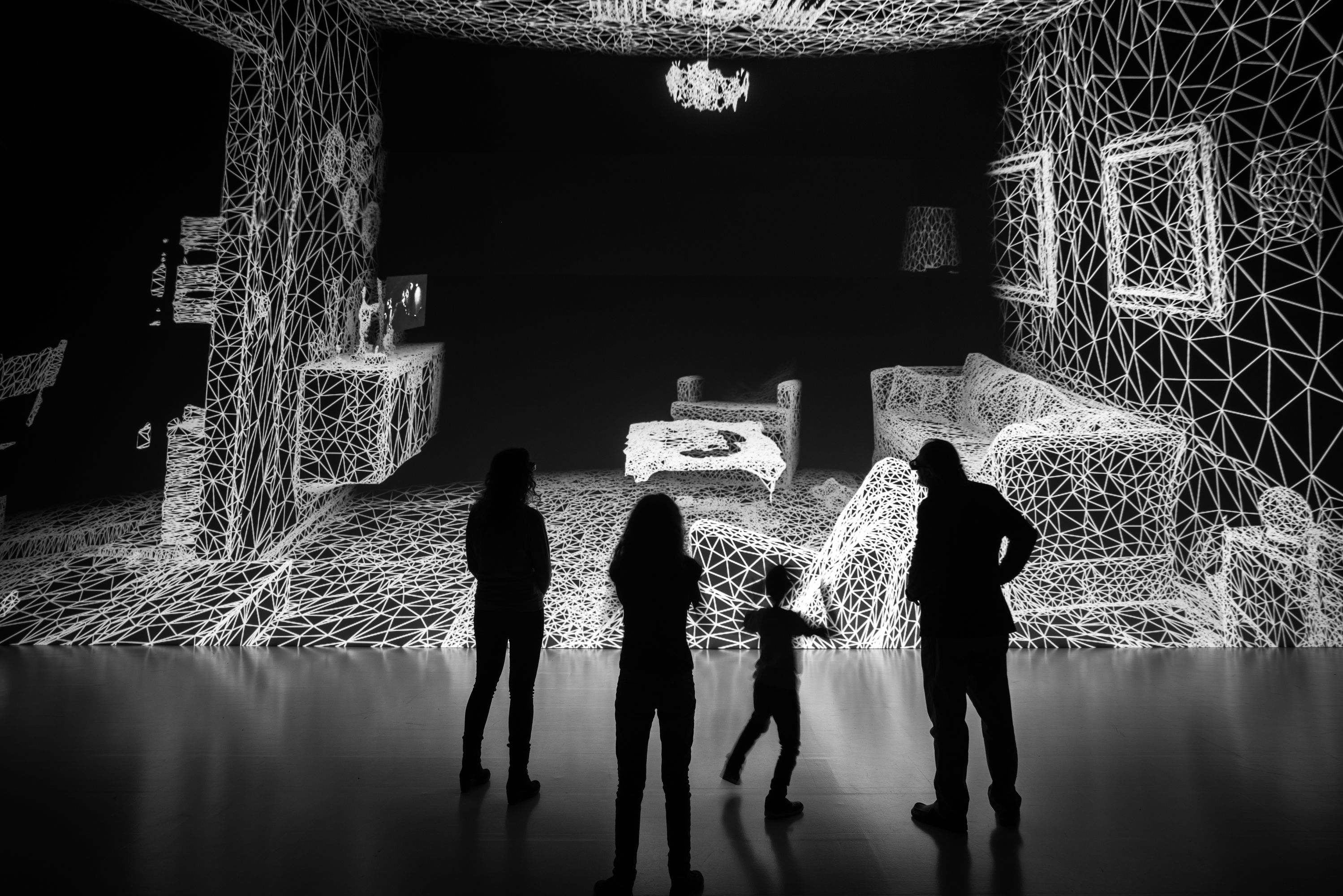Breathing room for freedom: How to benefit from digitalization rather than fear it A family of four looks over an art installation that looks like a digitalized version of a living room. Black and white photo